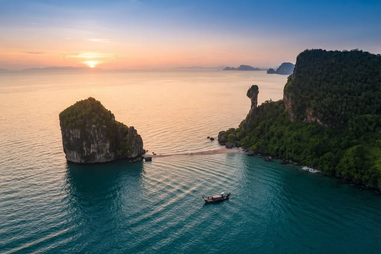 Aerial view of Chicken Island's chicken-head rock and a neighbouring islet with a longtail boat