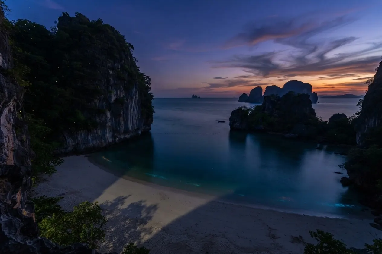 Hidden beach between cliffs at twilight with islands on the horizon