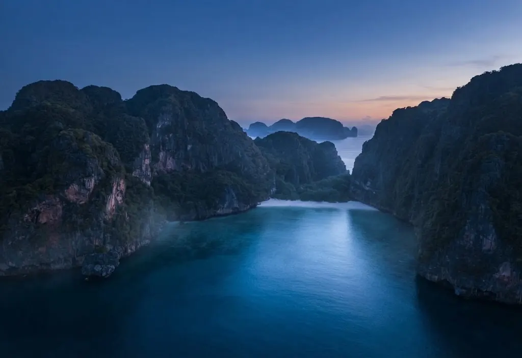 Calm sea channel between towering limestone islands at blue hour