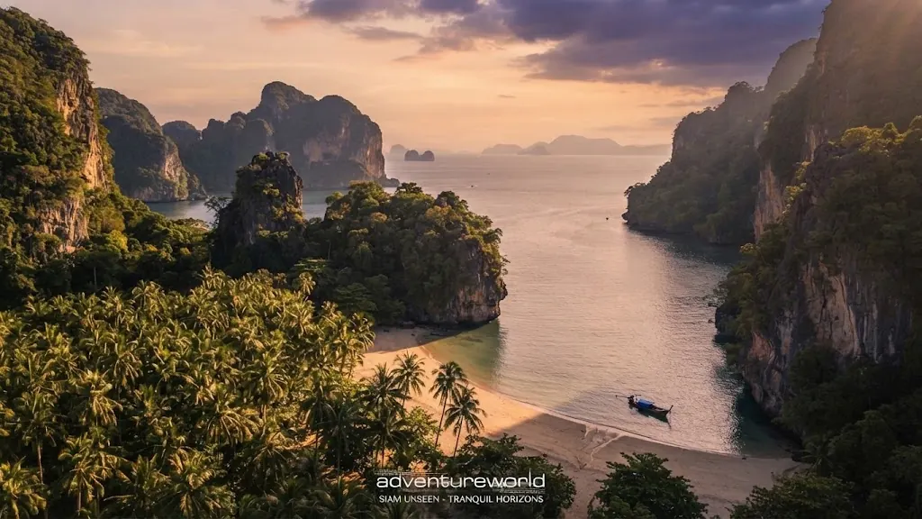 Aerial view of a jungle-backed bay and beach on the Railay peninsula with a longtail boat