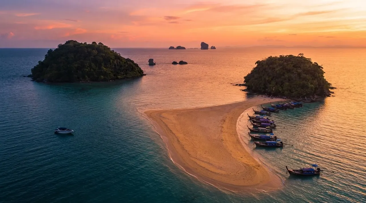 Aerial view of the sandbar linking two small islands with a line of longtail boats at sunset