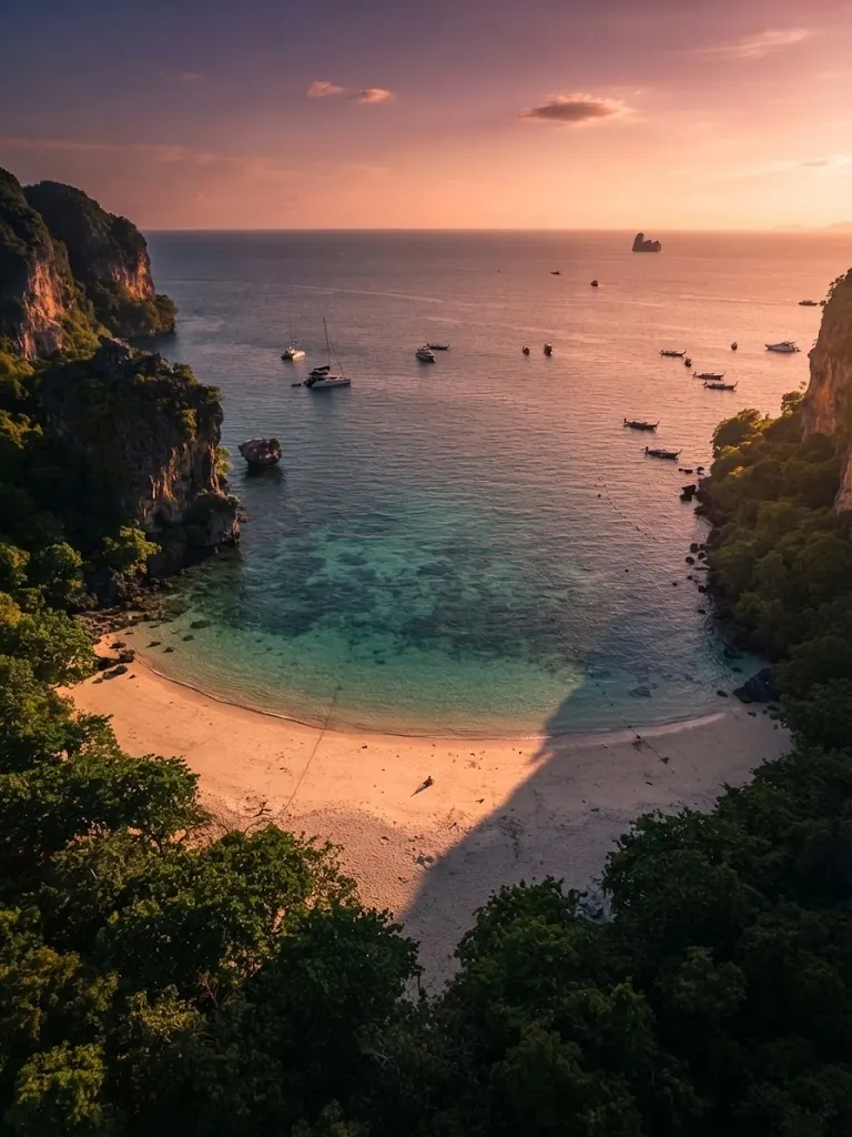Aerial view of a sheltered cove with anchored boats between jungle-covered cliffs